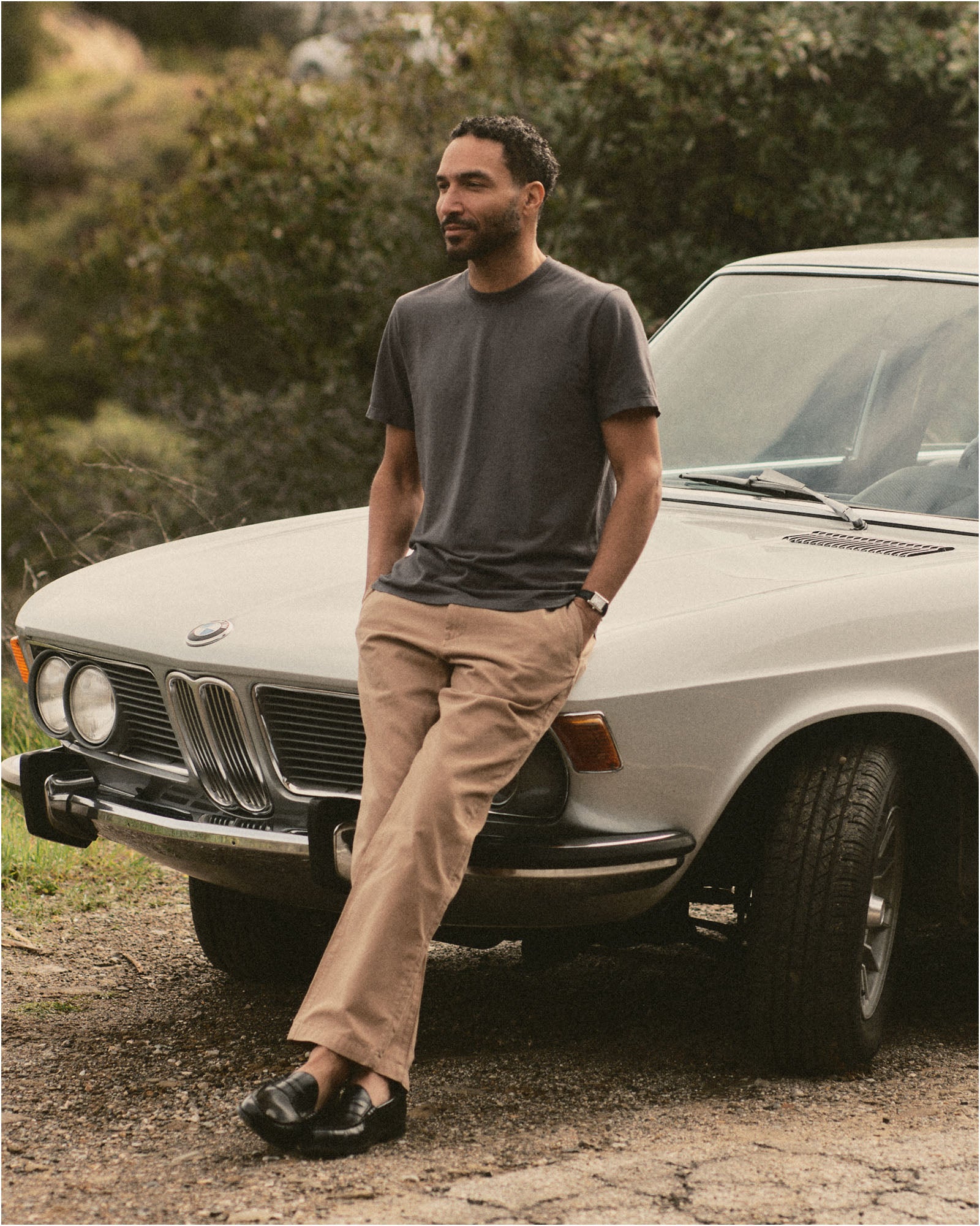 fit model leaning against a car wearing The Cotton Hemp Tee in Faded Black, Knits by Taylor Stitch