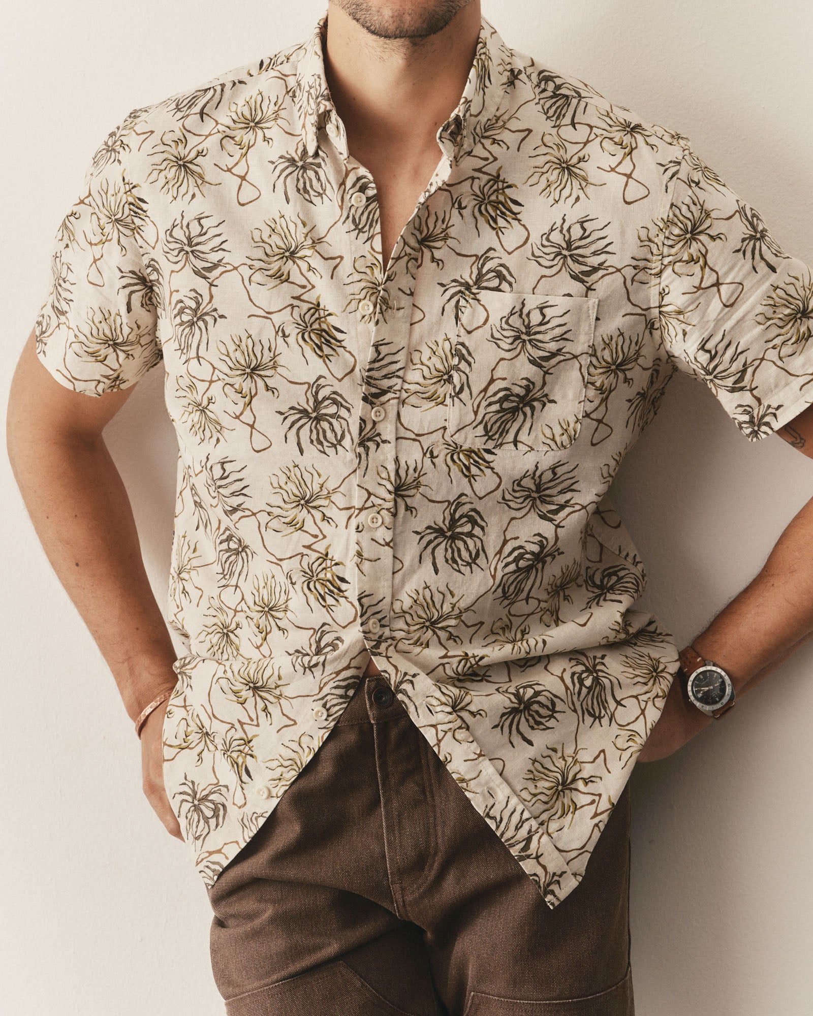 fit model leaning against the wall wearing The Short Sleeve Jack in Dried Palms, Wovens by Taylor Stitch