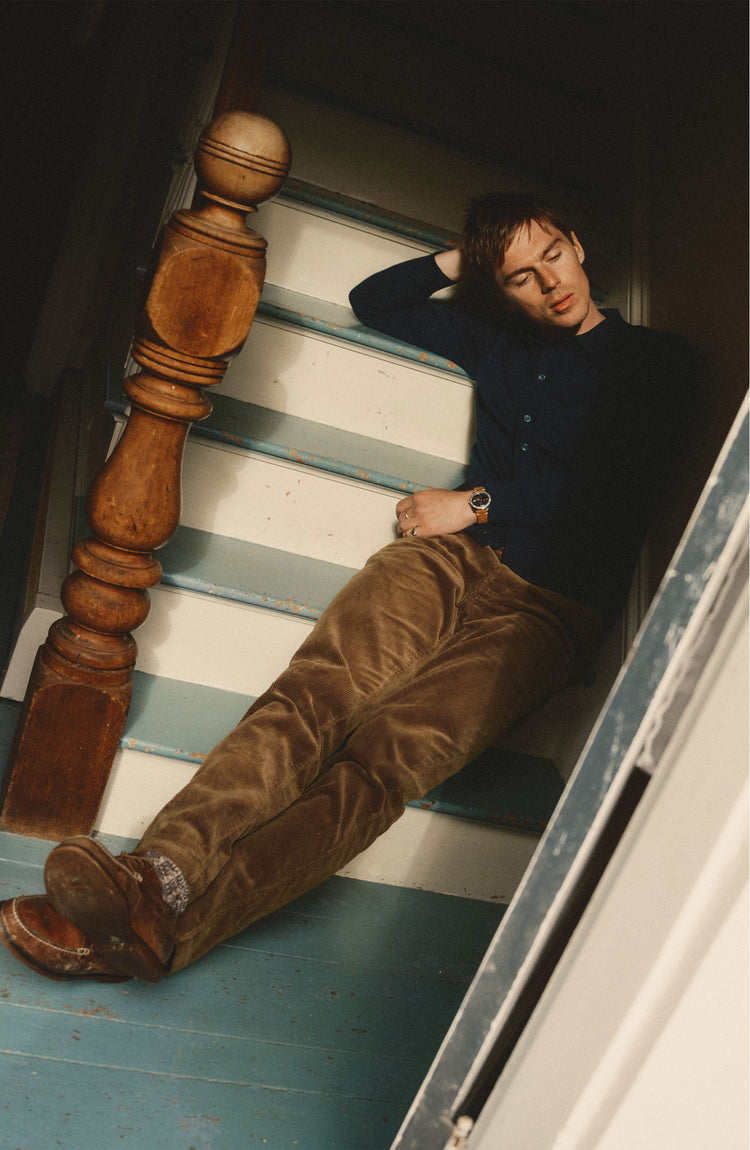 fit model sitting wearing The Carnegie Pant in Bourbon Corduroy