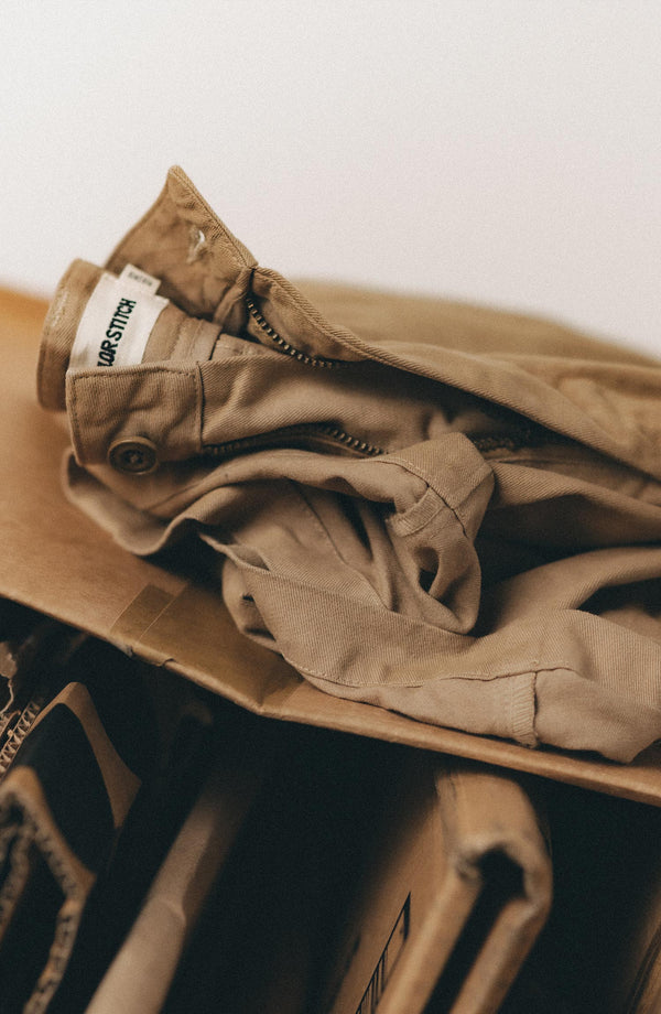 A pair of Foundation Pants folded on a black background, showing the back pocket.