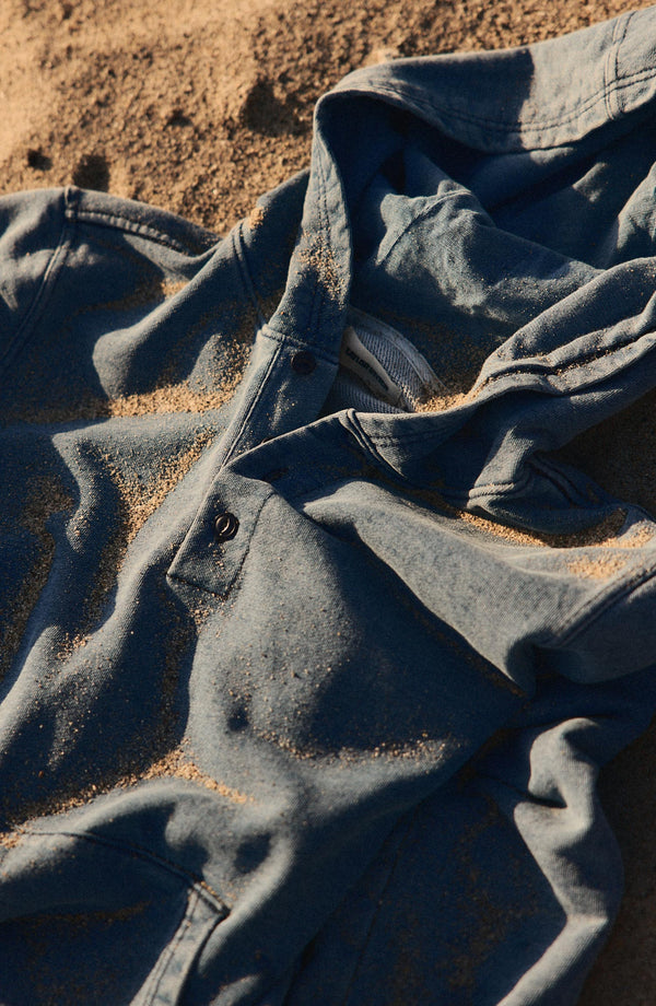 editorial flatlay of The Baja Pullover in Washed Indigo Terry on the beach