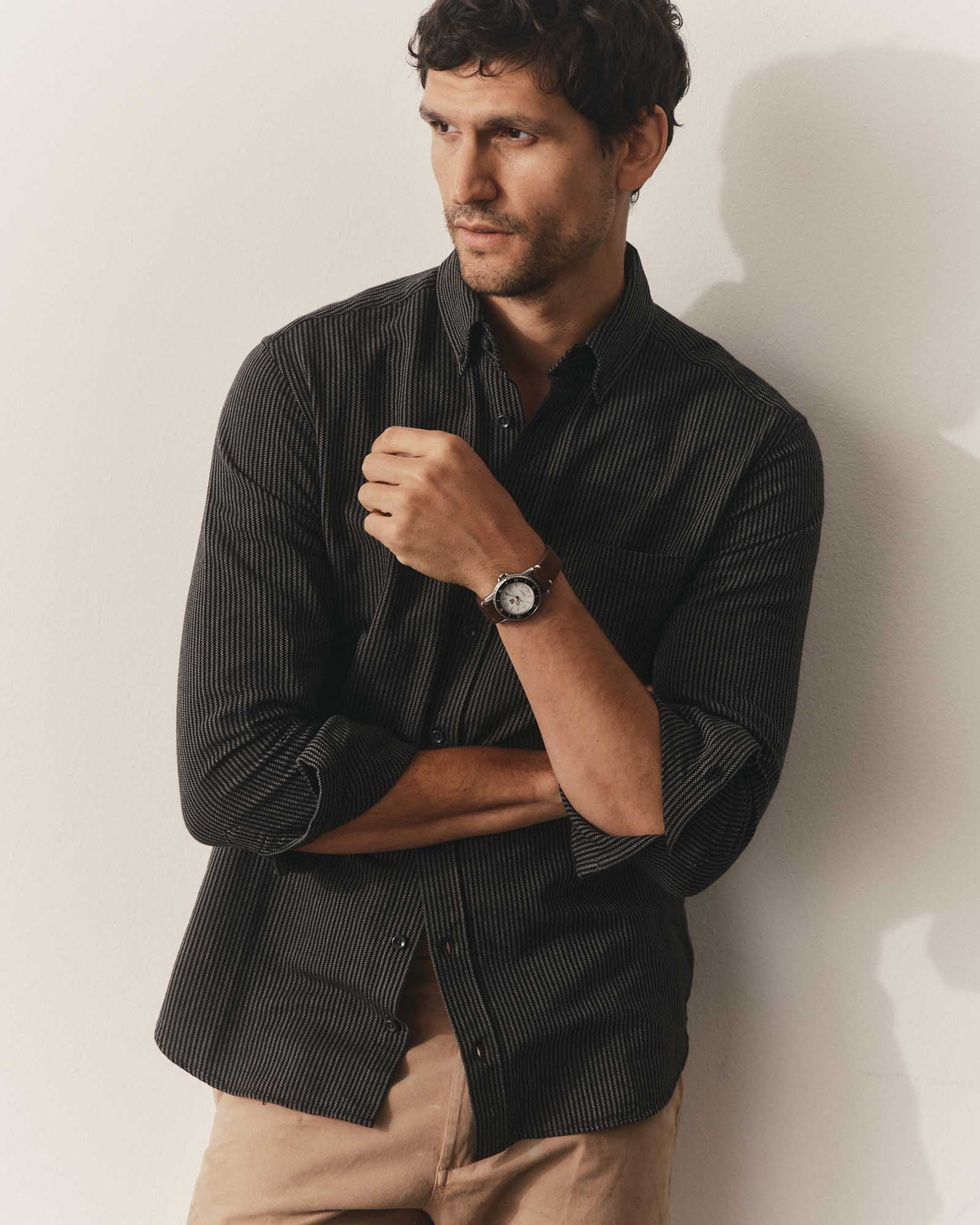 fit model leaning against the wall wearing The Jack in Roped Black Indigo, Wovens by Taylor Stitch