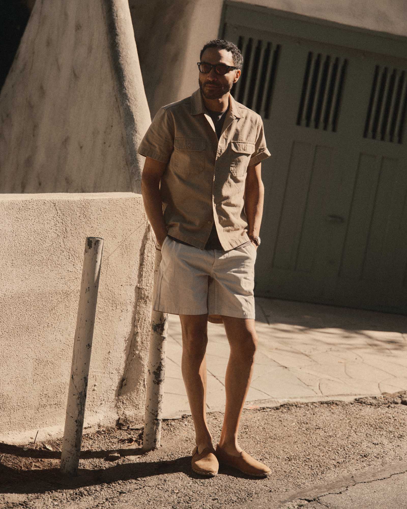 fit model leaning on a pole wearing The Short Sleeve Mechanic Shirt in Khaki Ripstop, Wovens by Taylor Stitch