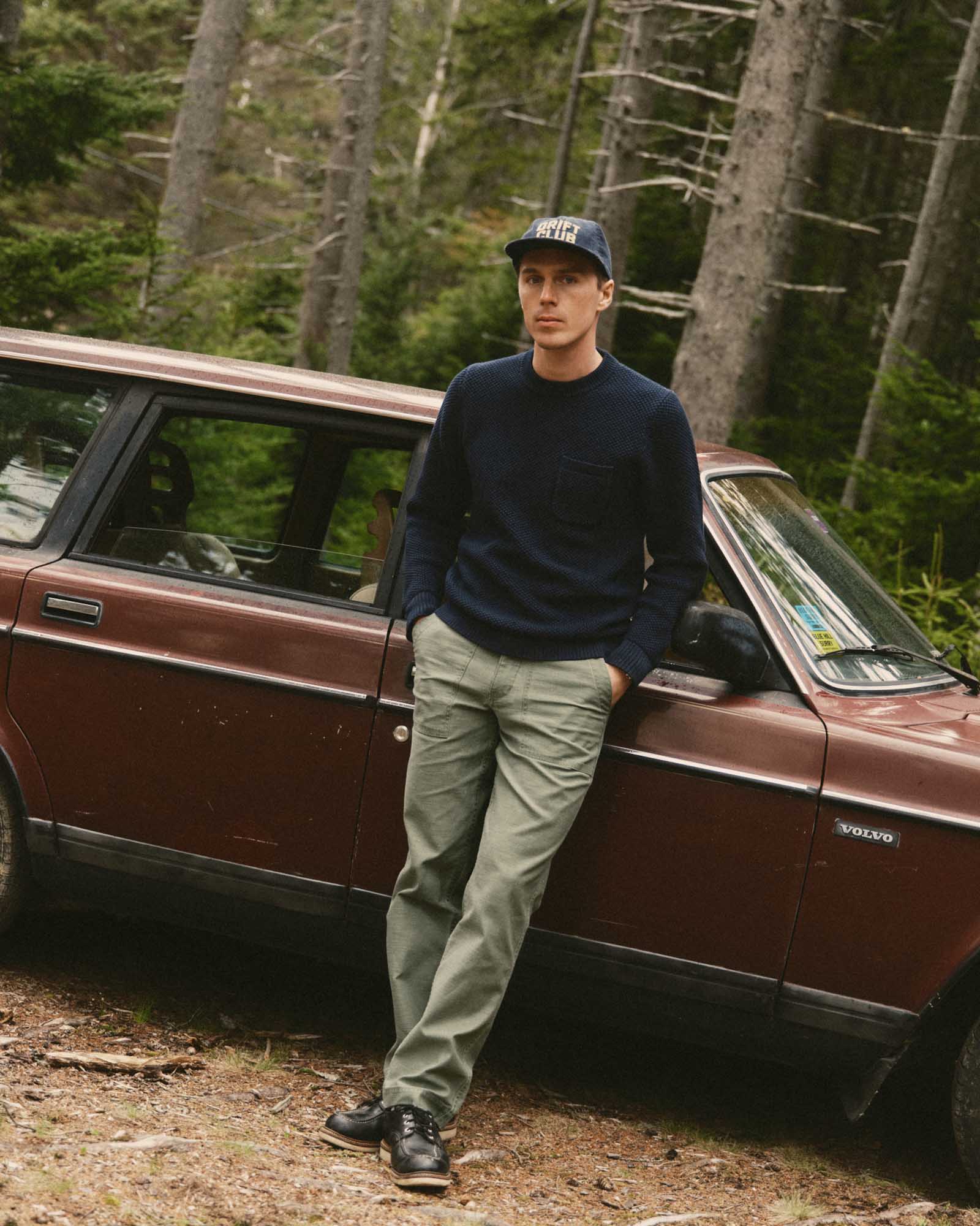 fit model sitting wearing The Surplus Pant in Field Olive Reverse Sateen, Bottoms by Taylor Stitch