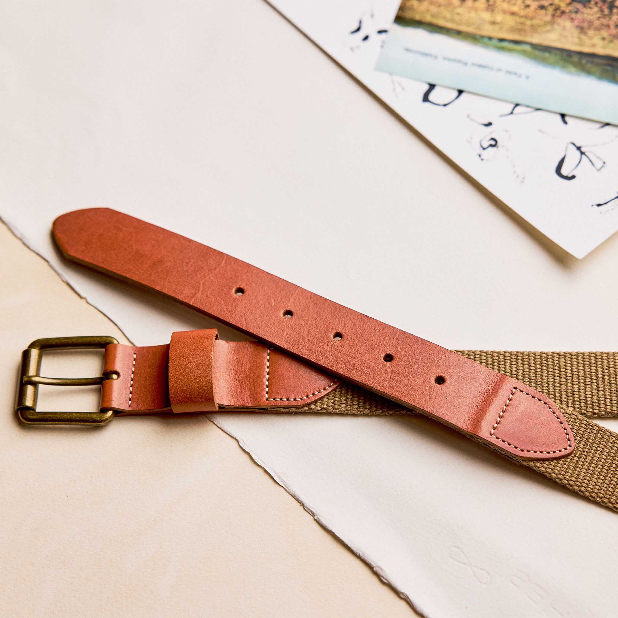 editorial image of The Webbed Belt in Whiskey on sheets of paper, Accessories by Taylor Stitch