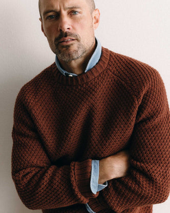 fit model with his arms crossed wearing The Fisherman Sweater in Heather Brick Merino