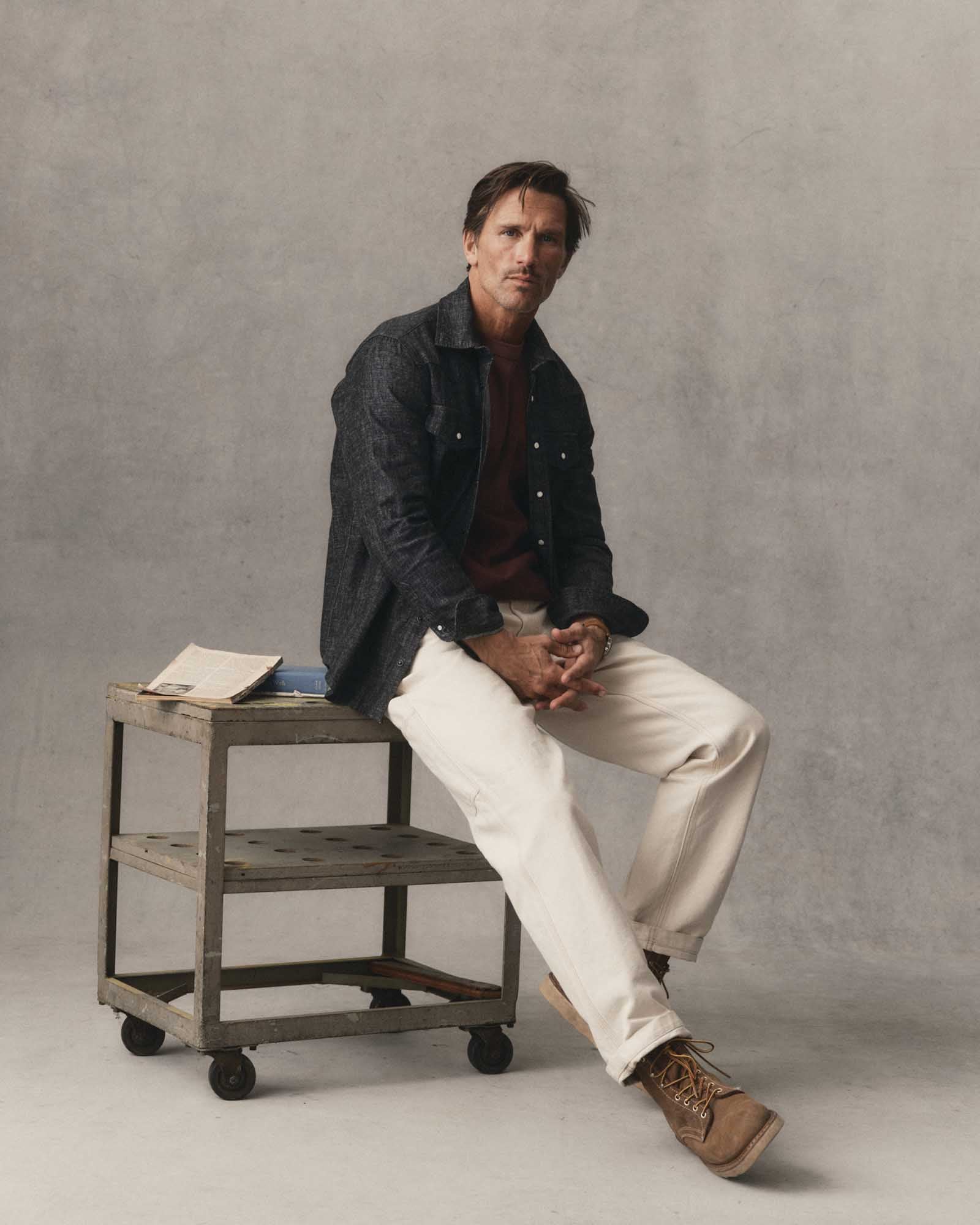 fit model sitting wearing The Glacier Shirt in Black Indigo Hemp Denim, Wovens by Taylor Stitch