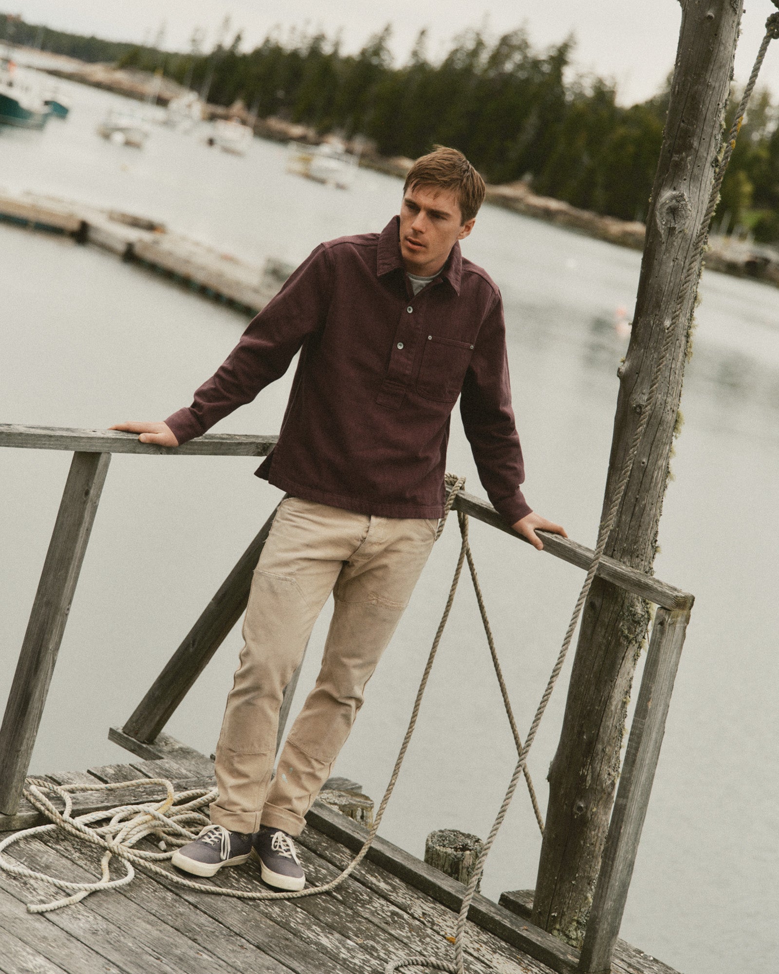 fit model sitting wearing The Milton Overshirt in Burgundy Slub Denim, Outerwear by Taylor Stitch