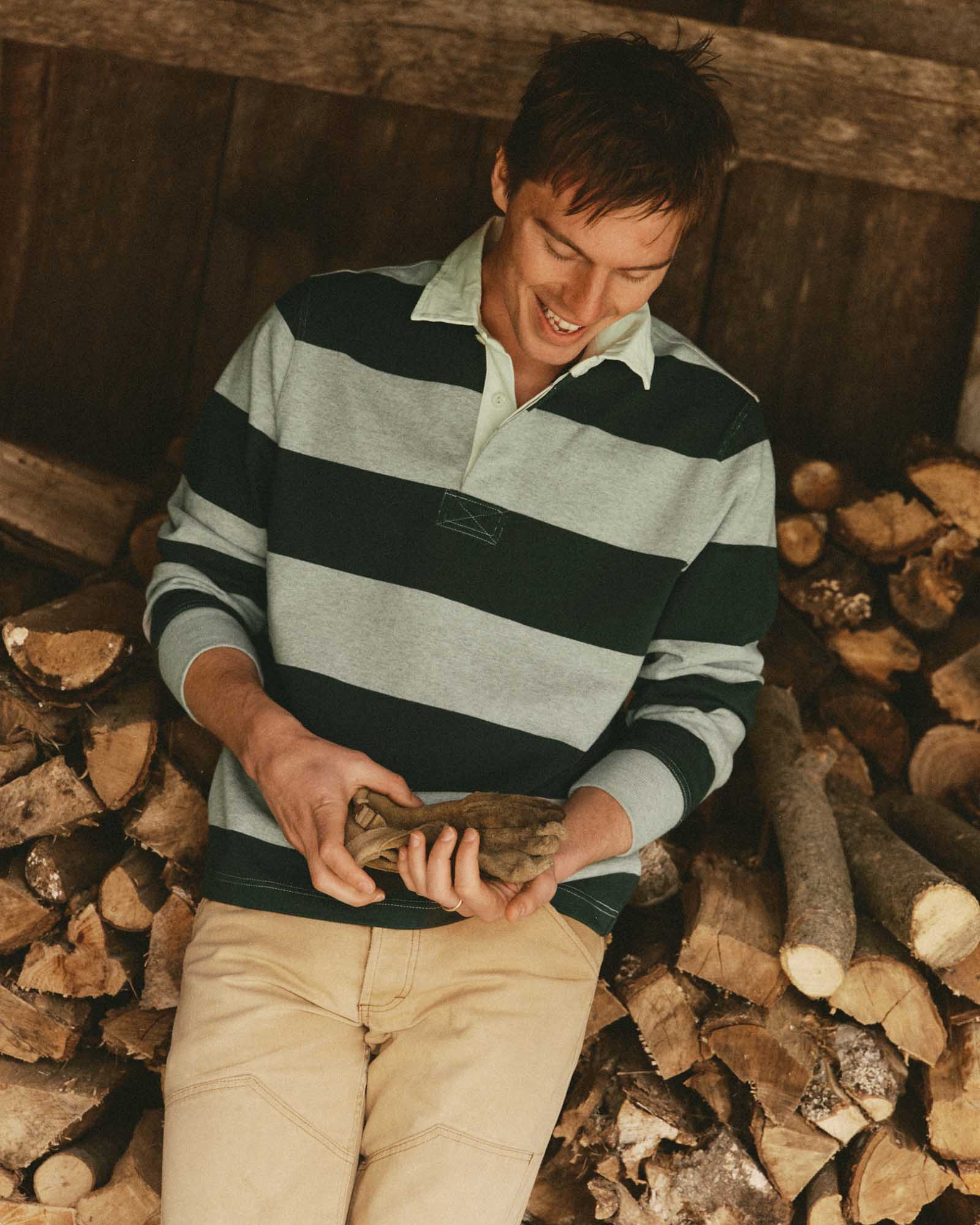 fit model sitting wearing The Rugby Shirt in Dark Forest Stripe, Knits by Taylor Stitch