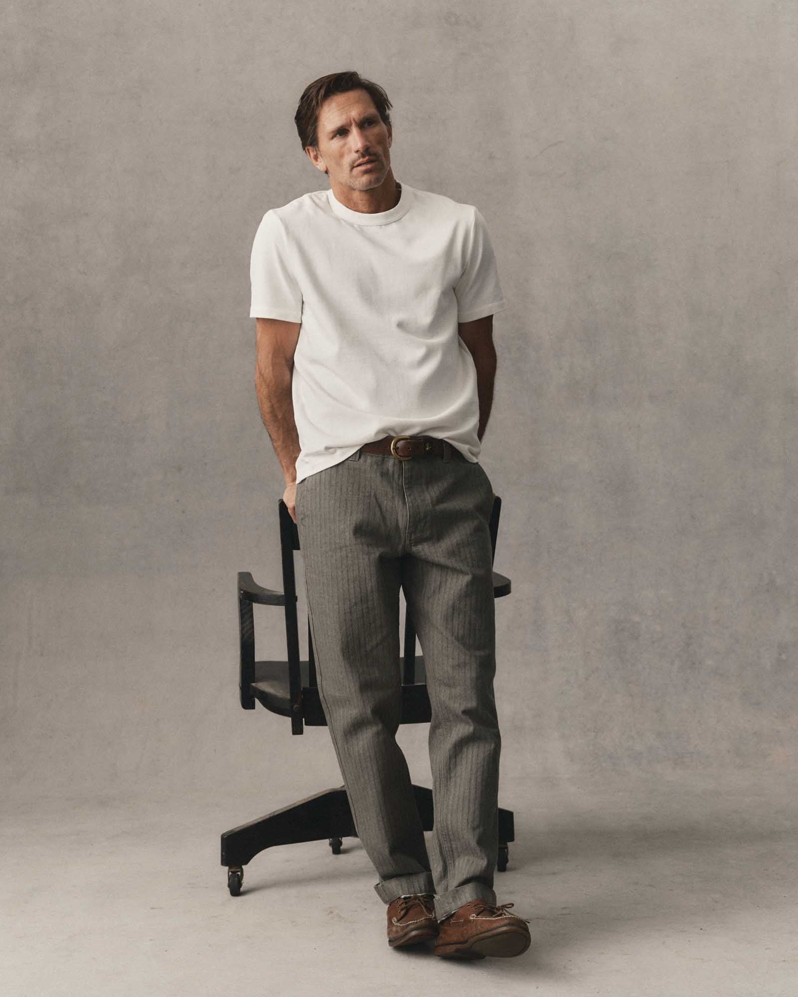 fit model leaning against a chair wearing The Organic Cotton Shop Tee in White, Knits by Taylor Stitch
