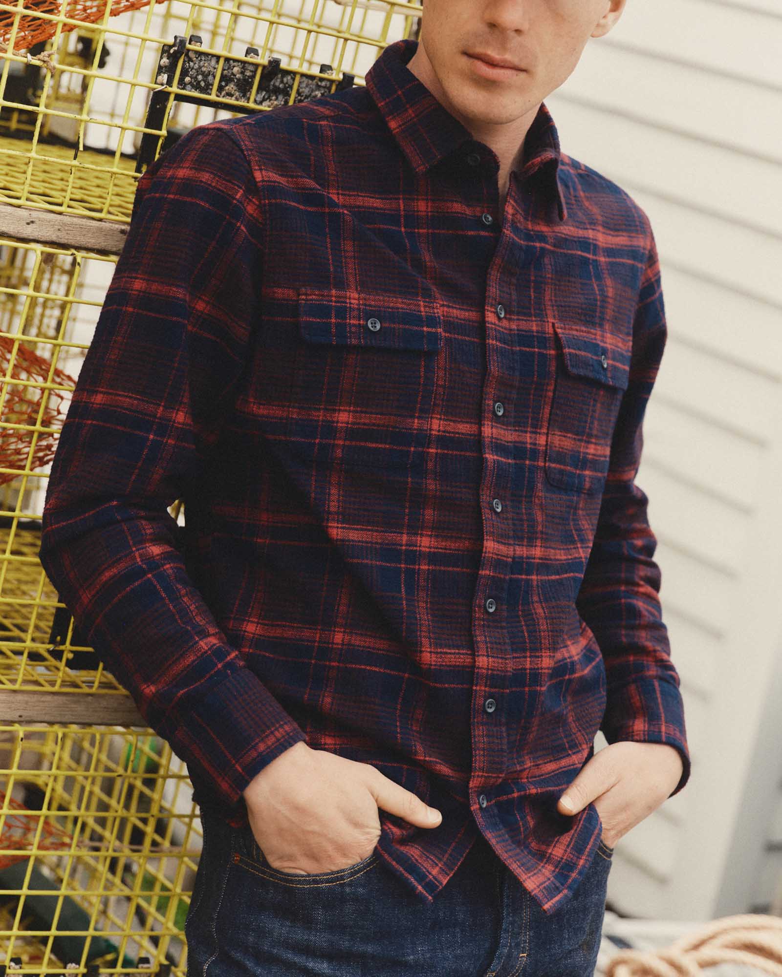 fit model leaning against crates wearing The Yosemite Shirt in Delaware Plaid, Wovens by Taylor Stitch