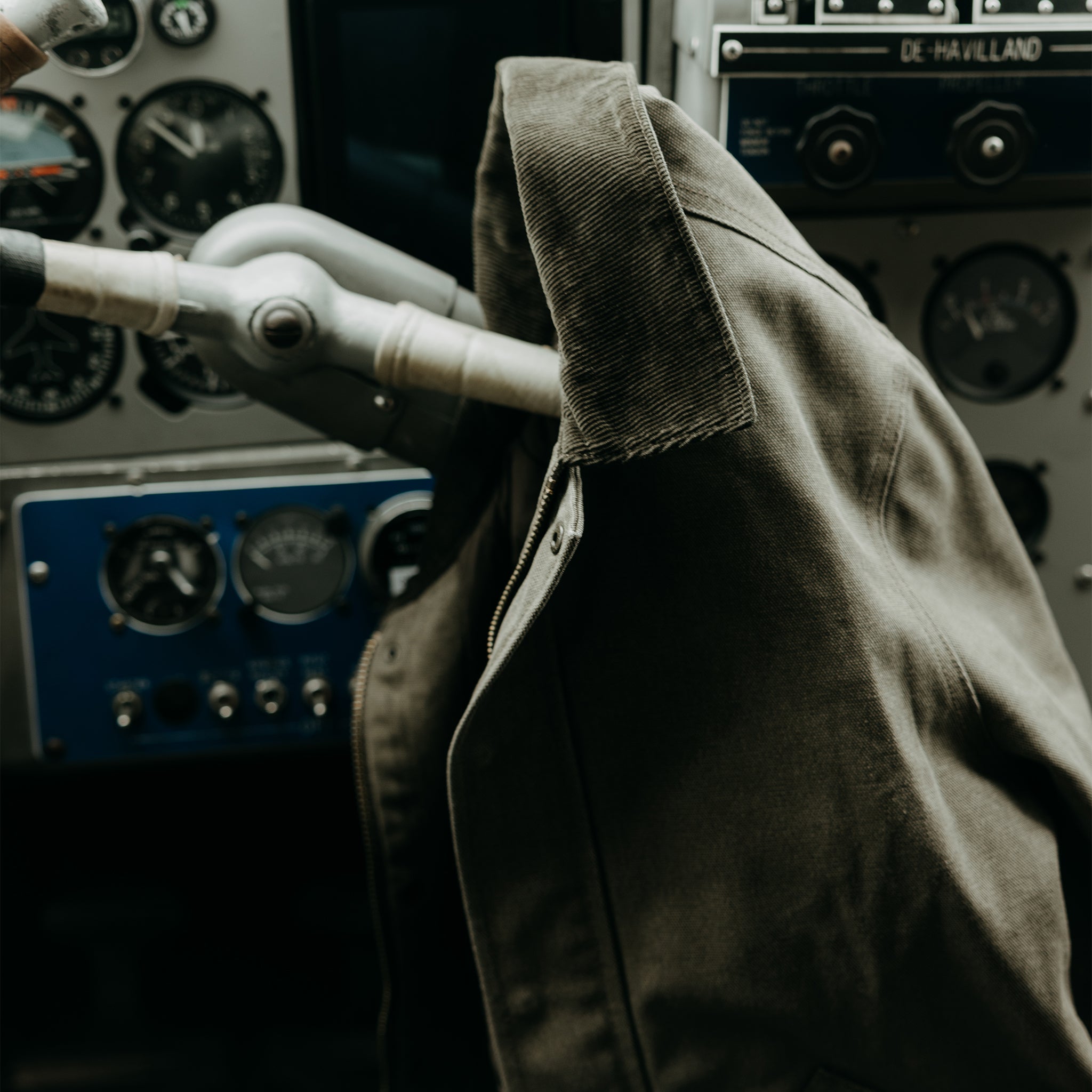 editorial image of The Workhorse Jacket in Stone Chipped Canvas hanging off of a seaplane wheel, Outerwear by Taylor Stitch