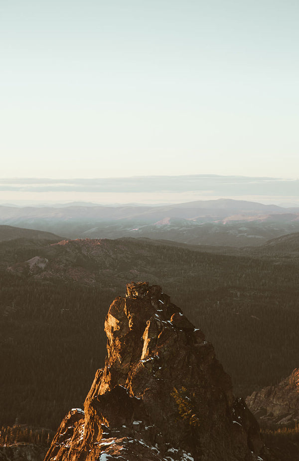 A dramatic rock outcrop with mountain ranges in the distance.