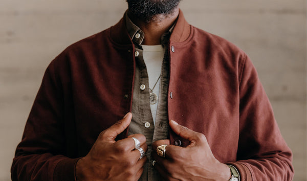 A green oxford shirt layered beneath a bomber jacket