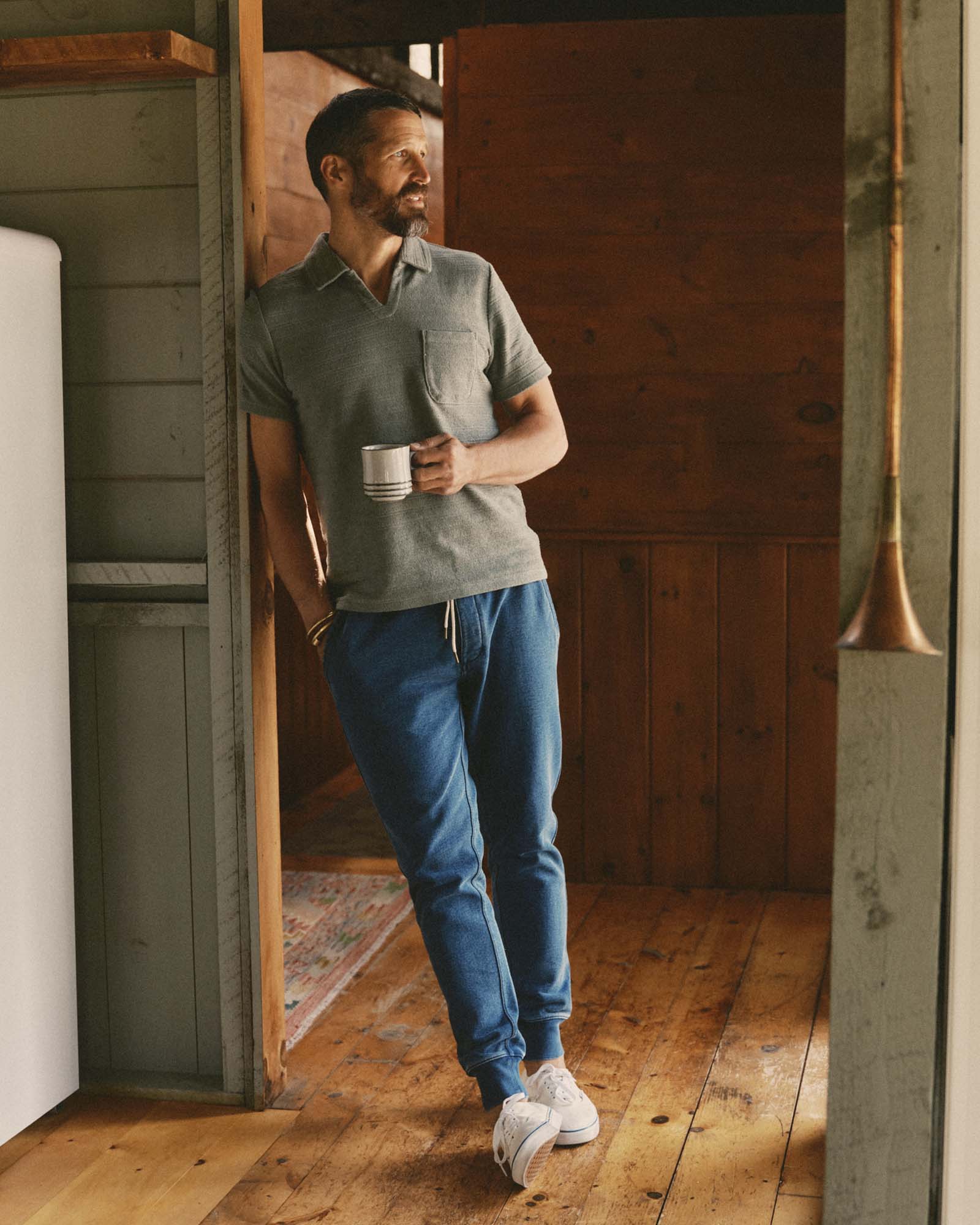 fit model leaning against the wall wearing The Sunset Pant in Washed Indigo Terry, Bottoms by Taylor Stitch