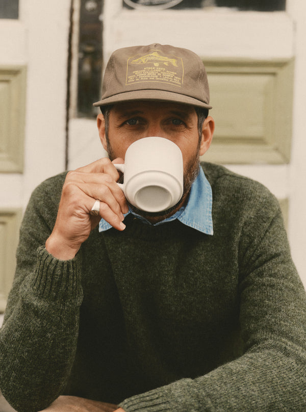 fit model posing in The Eastmoor Sweater in Spruce Wool and The Mercer Cap in Fish Supply