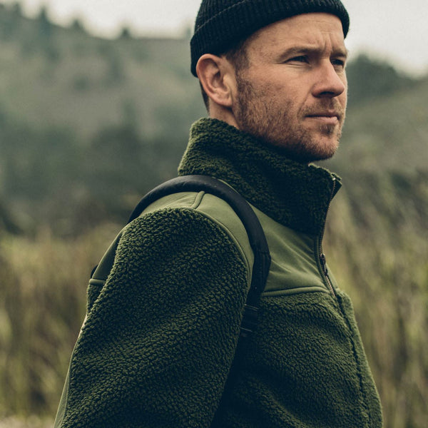 Our guy in a green fleece and hat, blurred grassland in the background.