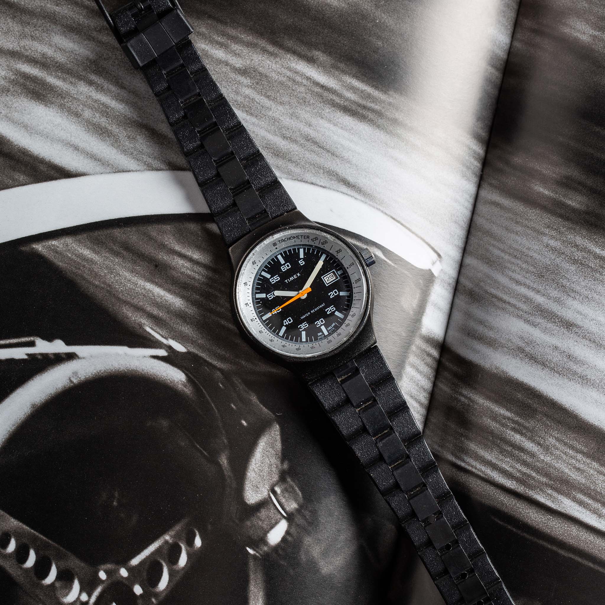 flatlay of the 1978 Timex Black Max, shown against a magazine, Accessories by Taylor Stitch